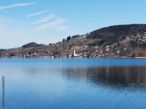 Schliersee in Oberbayern. Ort am Horizont mit lichtreflexion im Winter und Kirchdorf Sankt Sixtus 