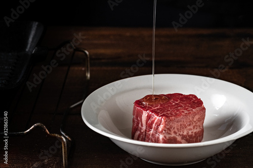 Foto Raw filet Mignon steak in a white plate is poured with olive oil before grilling