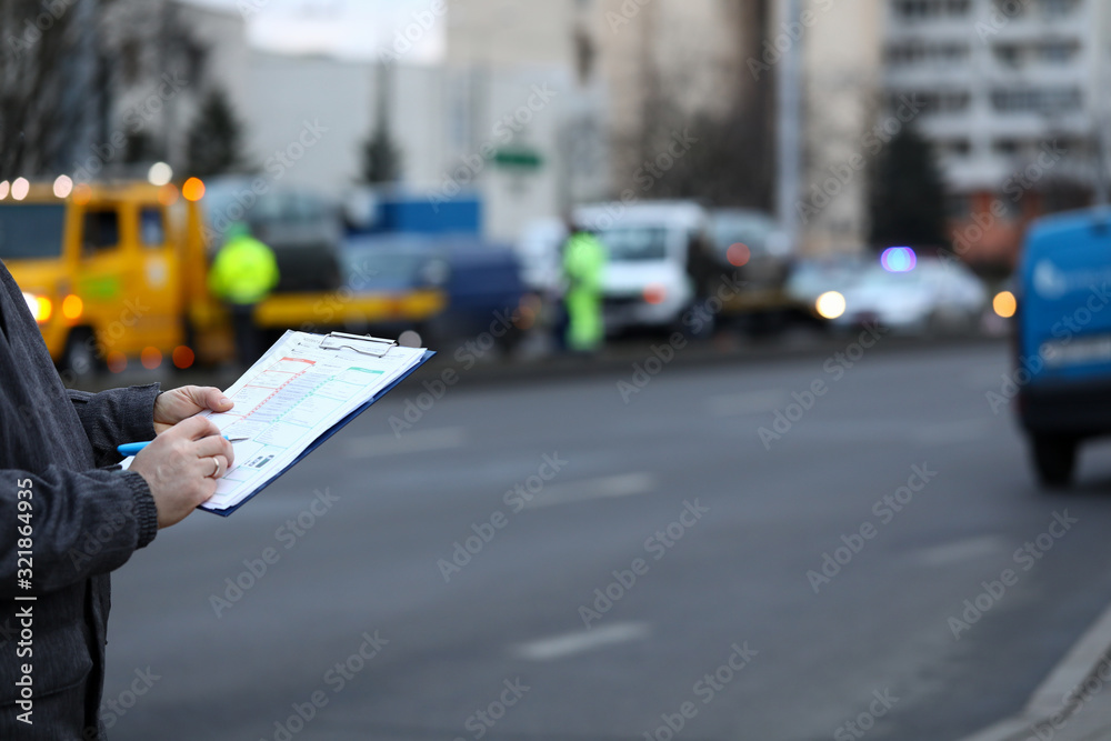 Filling out accident statement at scene accident. Man fills document standing on road. Driver draws up general statement accident, signs it. Claim settlement document. Document for insurance company. Filling out accident statement at scene accident. Man fills document standing on road. Driver draws up general statement accident, signs it. Claim settlement document. Document for insurance company.