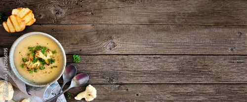 Roasted cauliflower and potato and soup. Top view table scene. Banner with corner border over a rustic wood background with copy space.