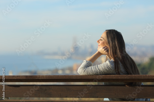 Relaxed woman sitting in a bench with closed eyes
