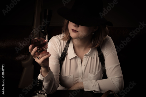 Canvas Print Retro mafia woman in a white blouse and a black hat sits at a table with air guns