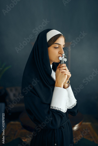 Young nun in a cassock prays crossed her arms