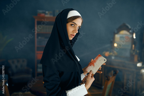 Crazy nun in a cassock holds bloody knife