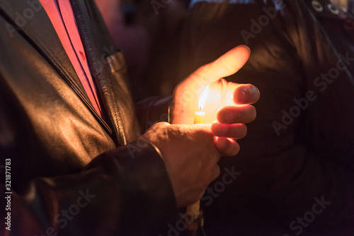 Closeup of people holding candle at night during church service photo