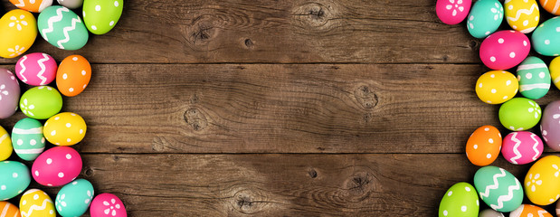 Colorful Easter Egg banner with double side border against a rustic old wood background. Above view with copy space.