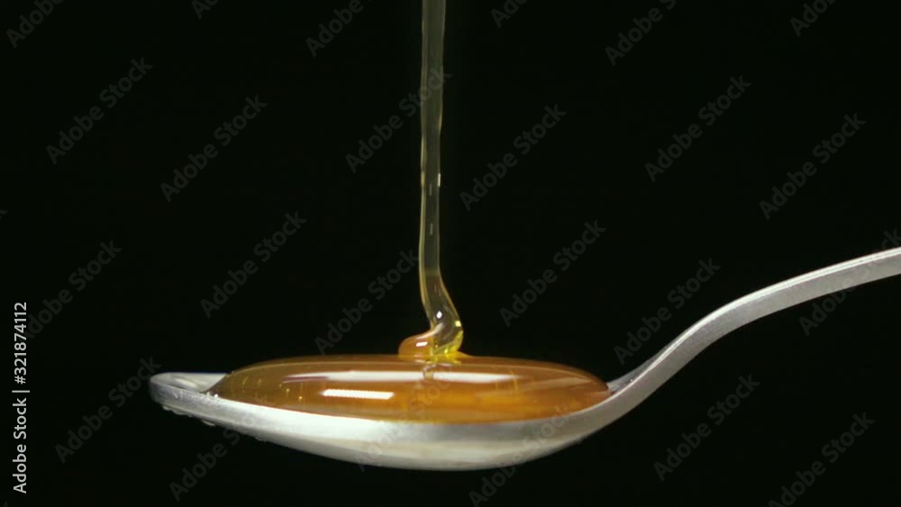 Slow motion shot : Close up honey dripping on the stainless tea spoon on black back ground. Slow motion shot : Close up honey dripping on the stainless tea spoon on black back ground.