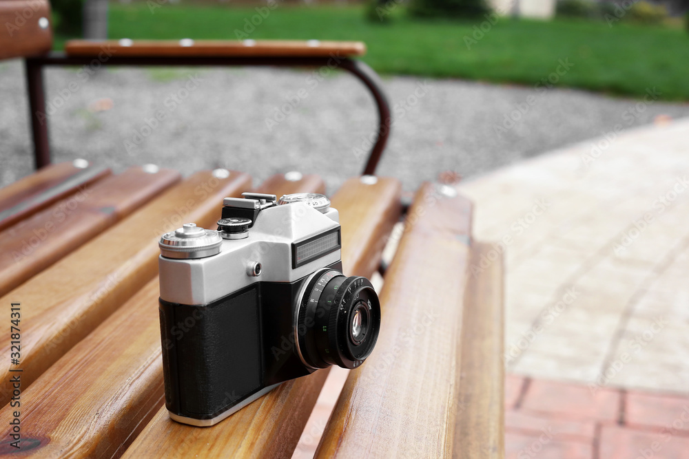 old camera on a bench on the street - obrazy, fototapety, plakaty 