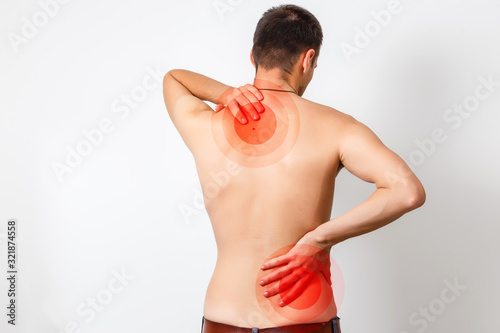 Rear view of a young man holding her neck in pain, isolated on white background, monochrome photo with red as a symbol for the hardening