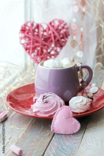 Cup of coffee with meringues and marshmallows on a red plate, hearts, illumination, against the background of a window, homeliness, Valentine's day, romantic greeting, happy birthday