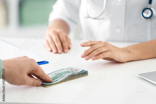 Patient giving bribe to doctor in clinic, closeup. Corrupted medicine