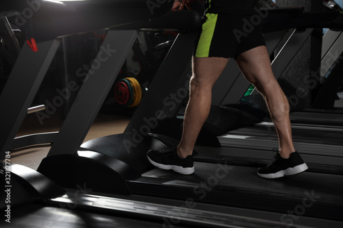 Man working out on treadmill in modern gym, closeup of legs