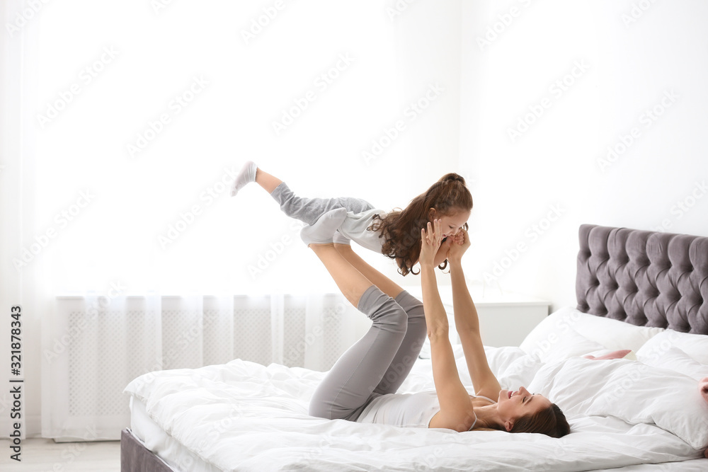 Happy mother with little daughter playing on bed Happy mother with little daughter playing on bed