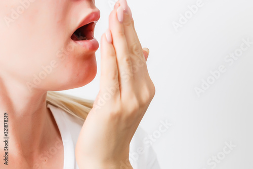 Health Care: Woman checking her breath with hand. Closeup portrait headshot sleepy young woman with wide open mouth Unrecognizable photo