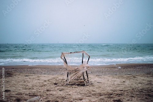 Old tattered chair on sandy beach