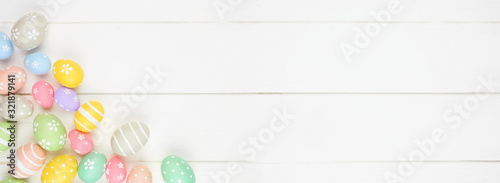 Pastel colored Easter Egg banner with corner border against a white wood background. Overhead view with copy space.