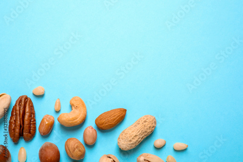 Different delicious nuts on light blue background, flat lay. Space for text