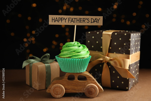 Composition with cupcake and gift boxes on brown table against blurred lights. Happy Father's day photo