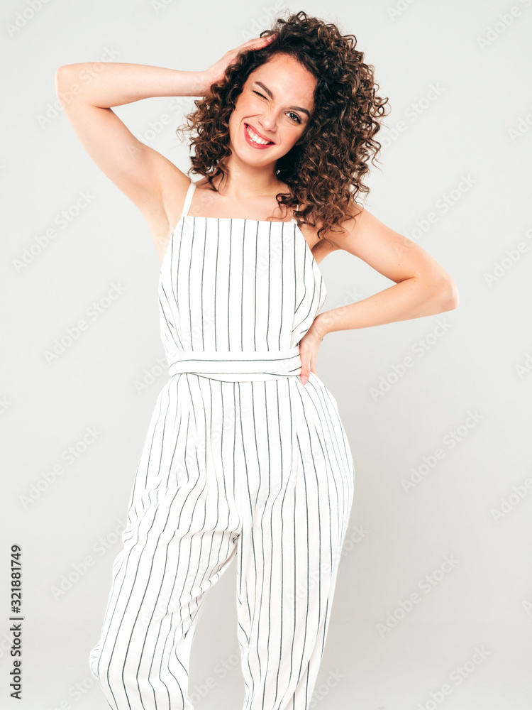 Obraz premium Portrait of beautiful smiling model with afro curls hairstyle dressed in summer hipster clothes.Sexy carefree girl posing in studio on gray background.Trendy funny and positive woman