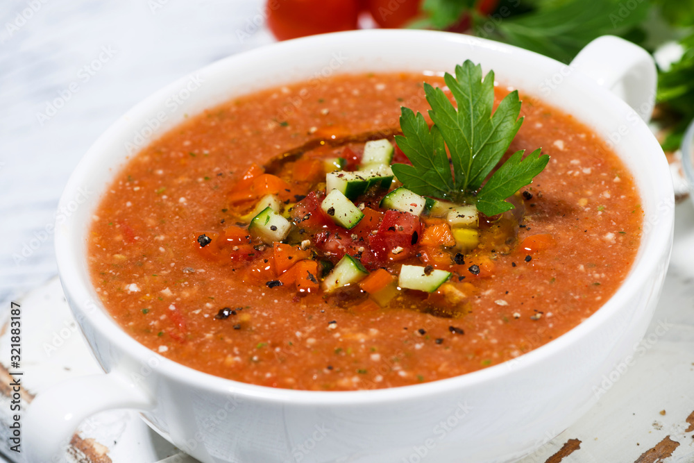 cold tomato soup in a bowl on white background, closeup cold tomato soup in a bowl on white background, closeup