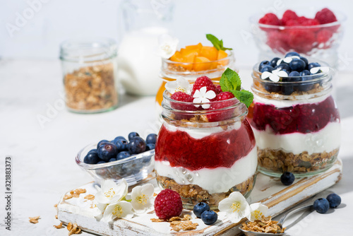 desserts with muesli, berry and fruit puree in jars on white background