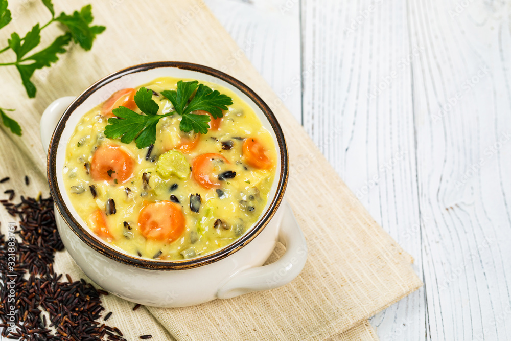 Cream of Chicken and Wild Rice Soup on White Wooden Background. Homemade Fresh Creamy Soup with Chicken, Carrot, Vegetables and Wild Rice. Selective focus.