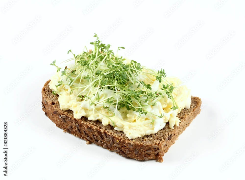 Egg salad over brown bread with garden cress. Homemade spread made from eggs, mayonnaise and mustard on white background