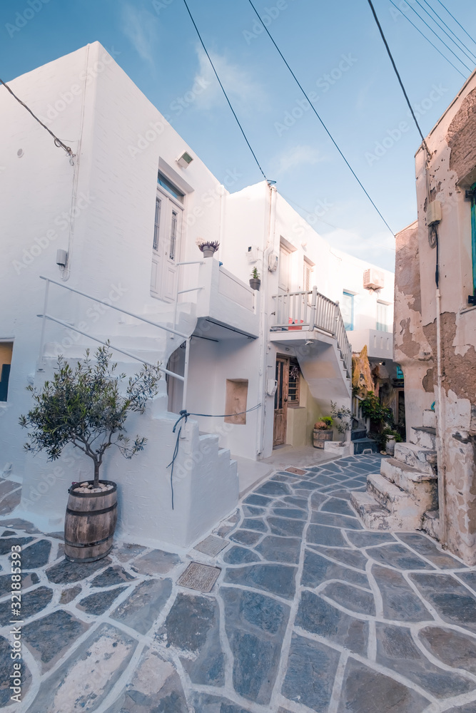 Amazing narrow streets of popular destination on Paros island. Greece. Traditional architecture and colors of mediterranean city. Blue doors, white buildings and bougainvillea flowers in paradise