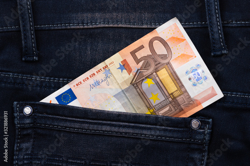 Fifty euro banknote money in pocket jeans pants background texture. 50 euro close up photo