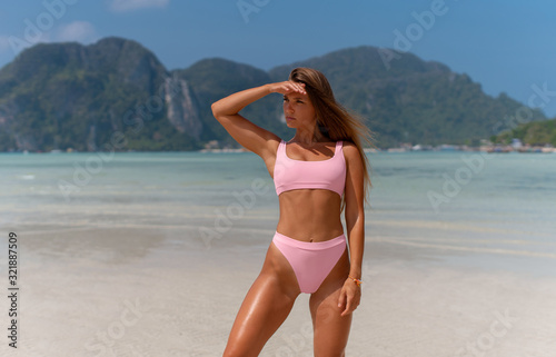 Obraz na płótnie Beautiful girl in a pink swimsuit enjoys the sun on the islands