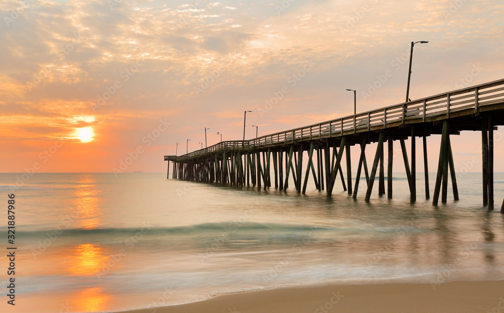 Fishing Pier at Sunrise at Virginia Beach, Virginia, USA. Virginia Beach, a coastal city in southeastern Virginia, lies where the Chesapeake Bay meets the Atlantic Ocean.