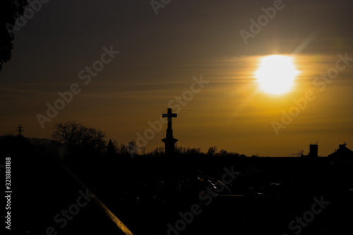 Silueta de una cruz en el horizonte con el sol detrás en el atardecer. photo