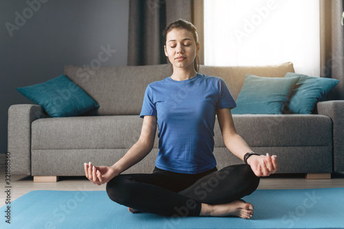 Barefooted fit young girl seeking for enlightenment in padmasana pose