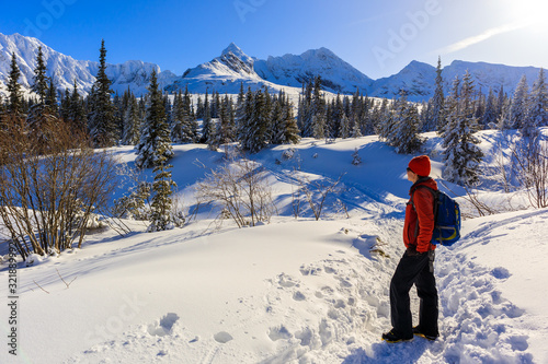 Young woman backpacker on walking trail in Gasienicowa valley during winter time, Tatra Mountains, Poland
