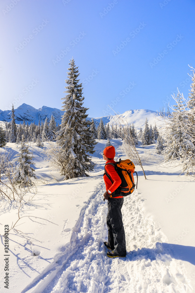 Young woman backpacker on walking trail in Gasienicowa valley during winter time, Tatra Mountains, Poland
