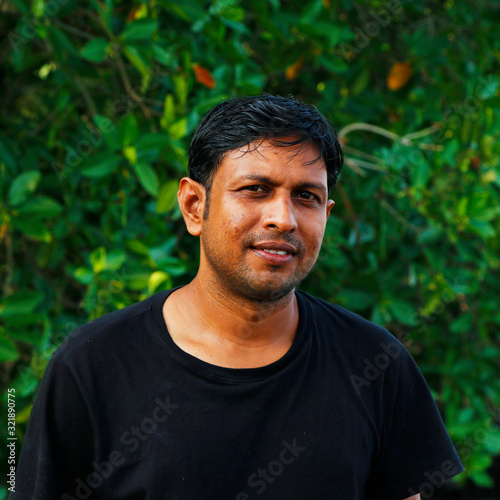 young indian gentleman possing with black tshirt with green background