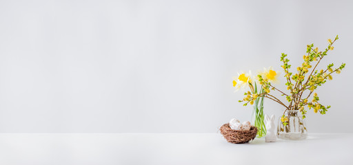 Home interior with easter decor. Willow branches in a glass vase, easter eggs on a light background