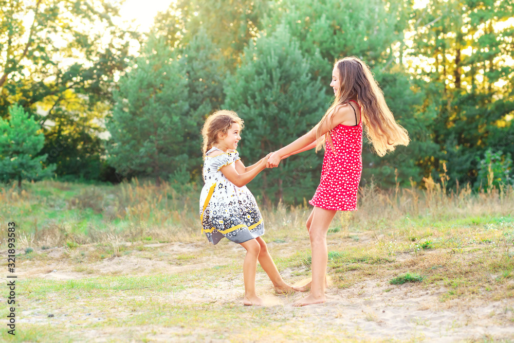 Two Happy cute little girls embracing and dancing at sunny summer day outdoors Two Happy cute little girls embracing and dancing at sunny summer day outdoors