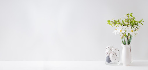 Home interior with easter decor. Spring flowers in a vase and easter eggs on a light background