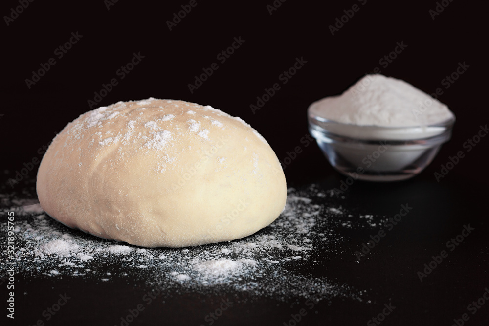 Yeast dough and bowl with flour on a dark background Yeast dough and bowl with flour on a dark background
