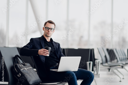 Young business man sitting on the computer at the airport waiting for the flight
