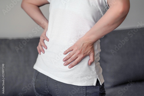 Woman suffer from low back pain. Hand of woman holding her waist backache in pain. Health care concept.