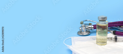 Vaccine or antibiotic bottle, syringe, stethoscope and medication masks on blue background. Health care, flu and virus cure cincept. photo