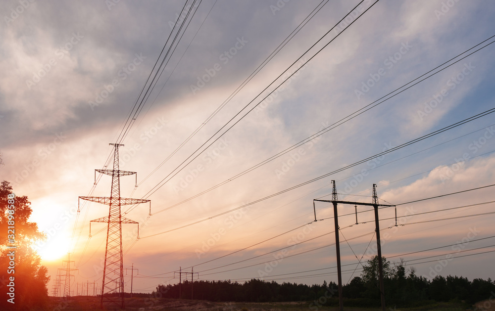A silhouette of high voltage power lines against a colorful sky at sunrise.