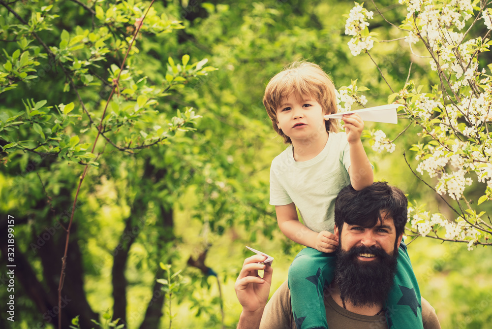 Father and son in forest on a meadow. Parent and child. Father and son holding ears. Dad with son and paper plane. Happy together. Father and son in forest on a meadow. Parent and child. Father and son holding ears. Dad with son and paper plane. Happy together.