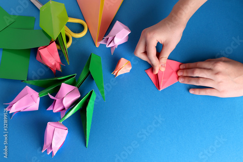 Mother's day gift. Hands of a child. Mother's Day, happy birthday, March 8, Women's Day, Valentine's Day. Bouquet of tulips from origami colored paper on a blue background. copy space. photo
