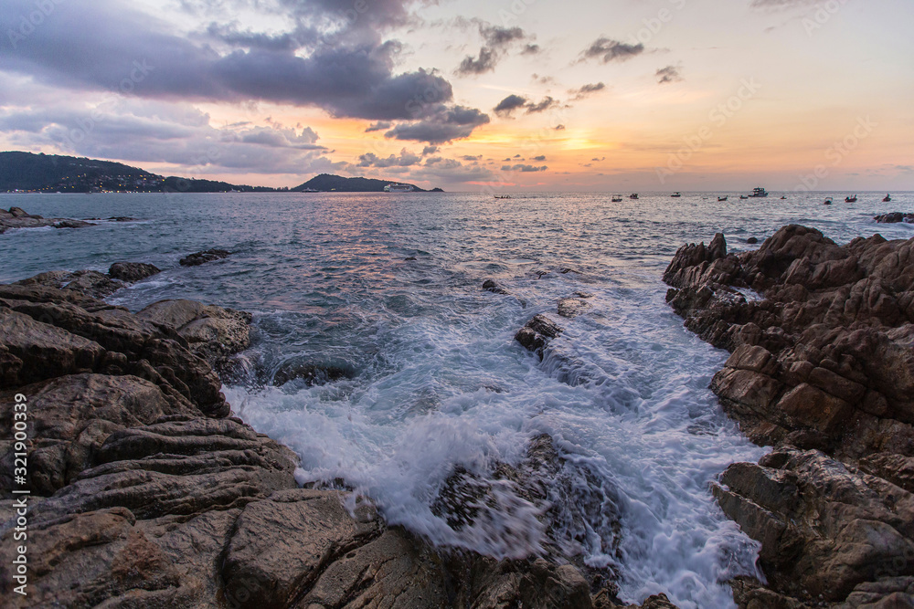 Obraz premium Stone coast, foamy waves and beautiful sunset. Thailand