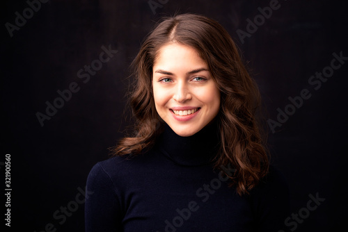 Close-up portrait of attractive young woman at dark background