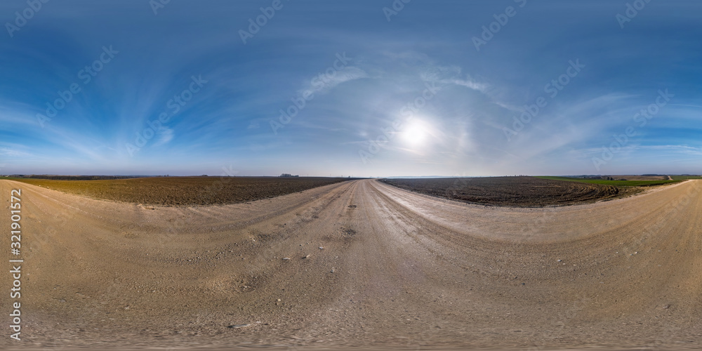 full seamless spherical hdri panorama 360 degrees angle view on gravel road among fields in early spring day with sun on clear sky with halo in equirectangular projection, ready for VR AR content