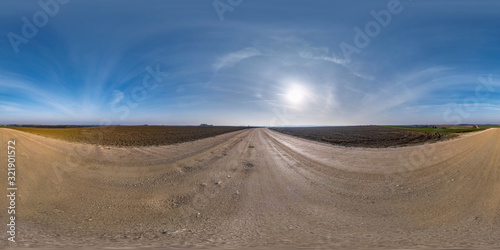 full seamless spherical hdri panorama 360 degrees angle view on gravel road among fields in early spring day with sun on clear sky with halo in equirectangular projection  ready for VR AR content